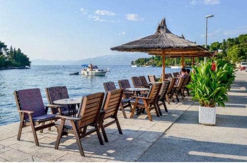 a row of tables and chairs with a boat in the water at Apartment Karla in Splitska