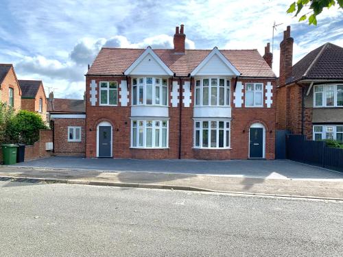 a large brick house with a lot of windows at Stanley Park House Peterborough - 3 bed, 3 bathroom, parking, garden in Peterborough