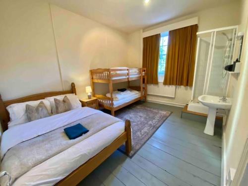 a bedroom with a bed and a bathroom with a sink at Carefree Cottage in Marstow