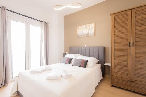 a bedroom with a large white bed with towels on it at Malvina Homes Knossou in Áno Fortétsa