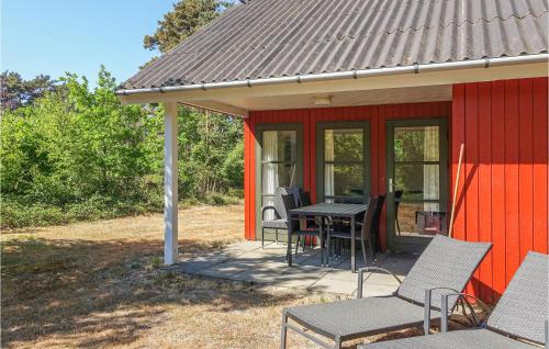 a red house with a table and chairs on a patio at Gorgeous Home In Aakirkeby With Wifi in Vester Sømarken