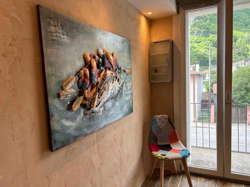 a painting hanging on a wall next to a chair at Larocca Tourist Home 3 Valbrenta in Carpane