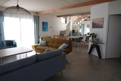 un salon avec un canapé et une salle à manger dans l'établissement Maison Bois, Les Conches 10 pers, à Longeville-sur-Mer