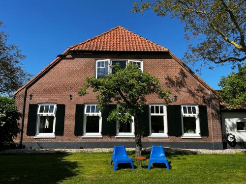 two blue chairs in front of a house at Hof van Eden in Ophemert