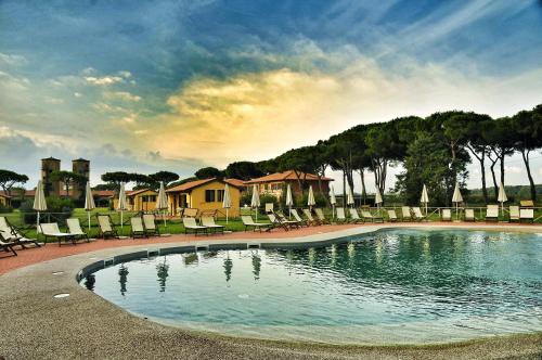 a large swimming pool with chairs and a house at La Fattoria di Tirrenia in Tirrenia