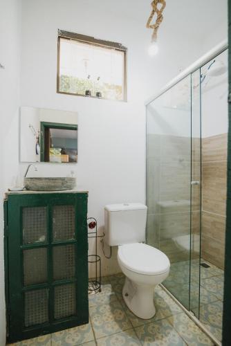 a bathroom with a toilet and a glass shower at Pousada Passaredo in Brumadinho