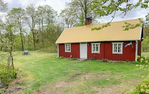 a red house with a yellow roof in a yard at Holiday Home Linghult, Isaka Stuga Eldsberga in Plingshult