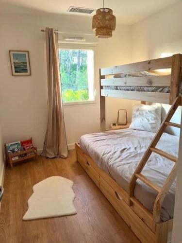 - une chambre avec des lits superposés en bois et une fenêtre dans l'établissement Villa neuve et moderne à 250 m de l'océan, classée 3 étoiles, à Lacanau