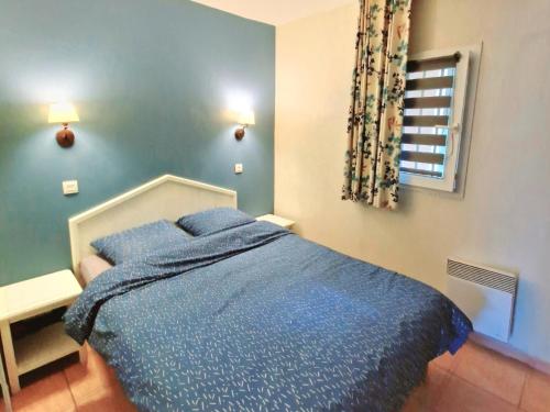 une chambre avec un lit avec des draps bleus et une fenêtre dans l'établissement Appartement t2 - bord de mer - Piscine, à Six-Fours-les-Plages