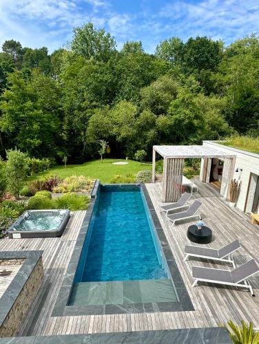 une piscine sur une terrasse en bois avec des chaises autour dans l'établissement Villa Uhaïna, à Biarritz