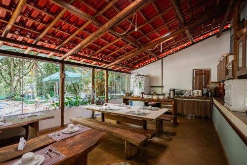 una sala da pranzo con tavoli in legno e una cucina di Pousada Passaredo a Brumadinho