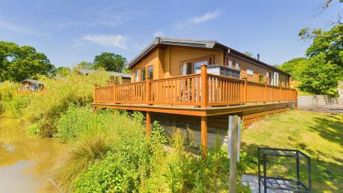a house with a deck on the side of a river at Poppy An Immaculate Lake side Lodge the Perfect Retreat, Sleeps 4 in Ryde