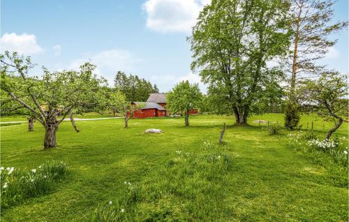 a field with trees and a red barn in the background at Awesome Home In Långserud With Wifi in Eldansnäs