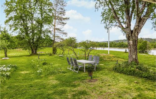 a table and chairs in a field with a tree at Awesome Home In Långserud With Wifi in Eldansnäs