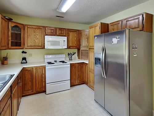 a kitchen with wooden cabinets and a stainless steel refrigerator at Just Another Day in Paradise in Surf City