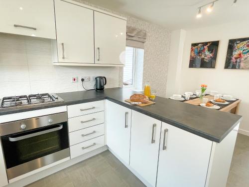 a kitchen with white cabinets and a stove top oven at Emerald House -3 Bed - Free Parking in Ferrybridge