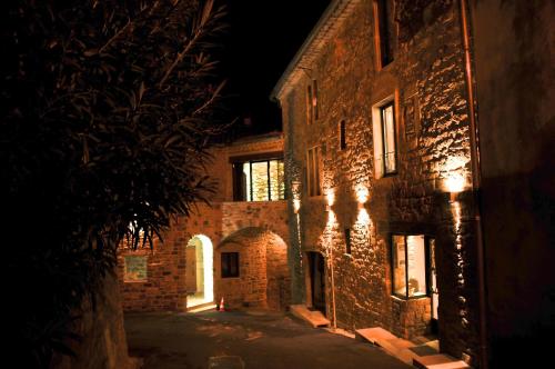 an old brick building at night with its lights on at La Maison du Passage - Chambres - Suites premium, Spa, Piscine et Restaurant in Martignargues