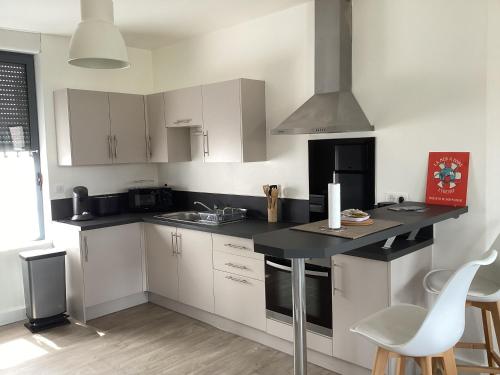 a kitchen with white cabinets and a black counter top at Les Halles centre ville parking en option in Étretat