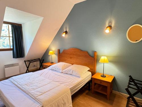 een slaapkamer met een bed met 2 lampen en 2 tafels bij Joli duplex pr 5p, parking, balcon, piscine été in Cauterets