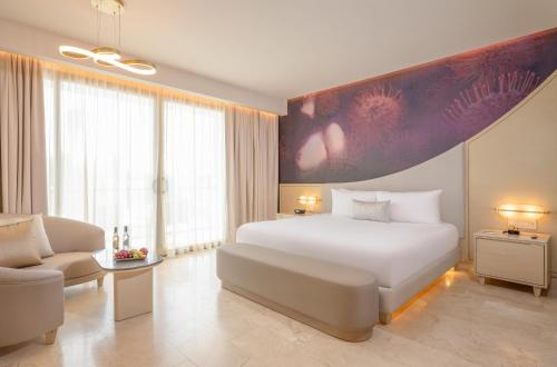 a bedroom with a large white bed and a chair at The Eden by Desire Riviera Maya All Inclusive - Couples Only in Puerto Morelos