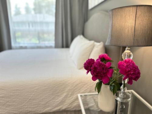 a vase of flowers on a table next to a bed at Modern Lux Family Rooms - KingBed - Near Sheppard W Station Toronto in Toronto