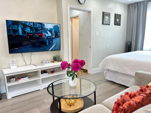 a living room with a tv and a vase of flowers at Modern Lux Family Rooms - KingBed - Near Sheppard W Station Toronto in Toronto
