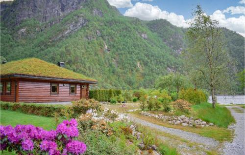 a cabin with a grass roof in a garden with flowers at Amazing Home In Matredal With Kitchen in Haugsvær