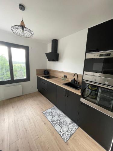 Il comprend une cuisine avec des appareils en noir et blanc et du parquet. dans l'établissement Maison 2 chambres, à Coucouron