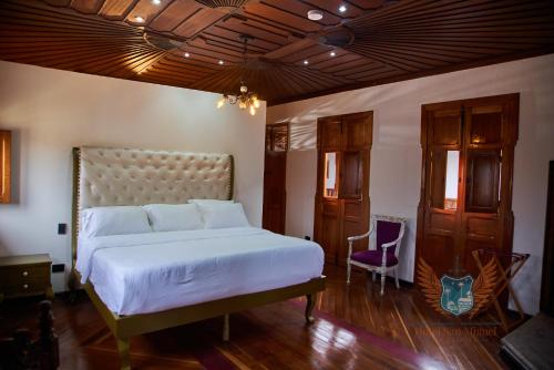 a bedroom with a white bed and a purple chair at Hotel San Miguel de Salento in Salento