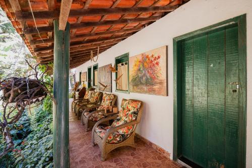 una veranda con sedie e una porta verde di Pousada Passaredo a Brumadinho