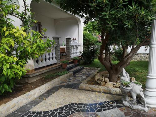 a garden with a tree and a white building at Apartment in Lopar with sea view, terrace, air conditioning, washing machine 593-3 in Lopar