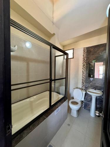 a bathroom with a tub and a toilet and a sink at Hotel Portal Dorado in Marinilla