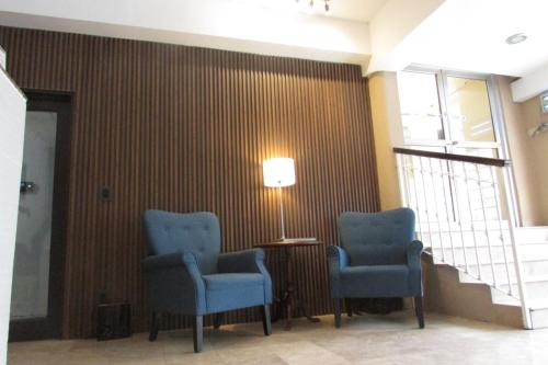a waiting room with two blue chairs and a lamp at Hotel Plaza in Sabinas