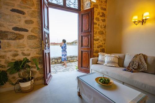 a living room with a couch and a person looking out the door at Villa Electra in Halki