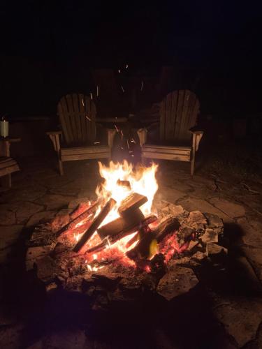 a fire with two chairs and a fire pit at night at Drift in Goderich