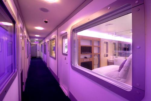 a corridor of a hospital room with purple lighting at YOTELAIR Amsterdam Schiphol Transit Hotel in Schiphol