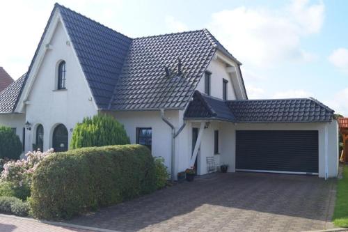 a white house with a black roof and a garage at Schönes Ferienhaus in Radewege mit schönem Garten in Radewege