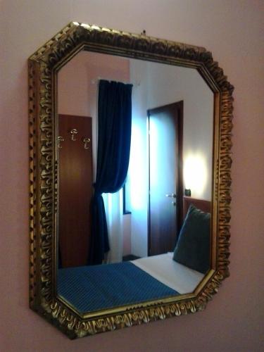 a mirror on a wall with a bed in a room at Hotel San Giorgio in Bergamo