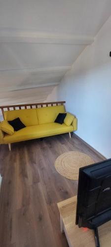 - un canapé jaune dans le salon avec une télévision dans l'établissement Un Souffle d'Air, à Valensole