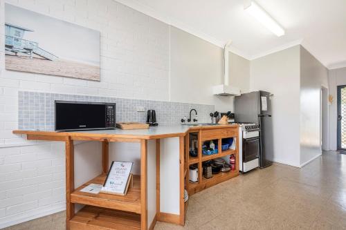 a kitchen with a counter with a sink and a refrigerator at Windsurfer Beach Chalet 2 in Lancelin