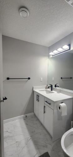 a white bathroom with a sink and a mirror at fabulous and cozy guest suite in Calgary