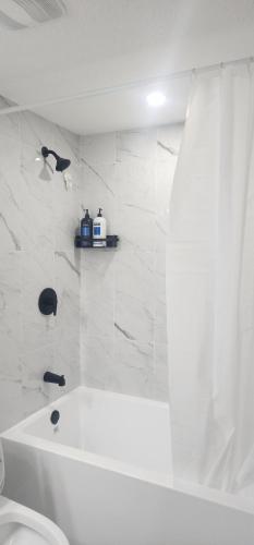 a white bathroom with a tub and a toilet at fabulous and cozy guest suite in Calgary