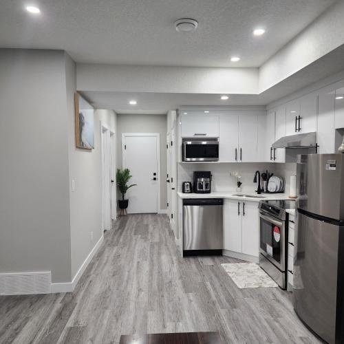 a kitchen with white cabinets and stainless steel appliances at fabulous and cozy guest suite in Calgary