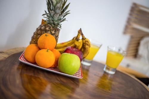 a plate of fruit on a table with two glasses of orange juice at Ammos Luxury Suite - in der Nähe des Strandes von Faliraki in Faliraki