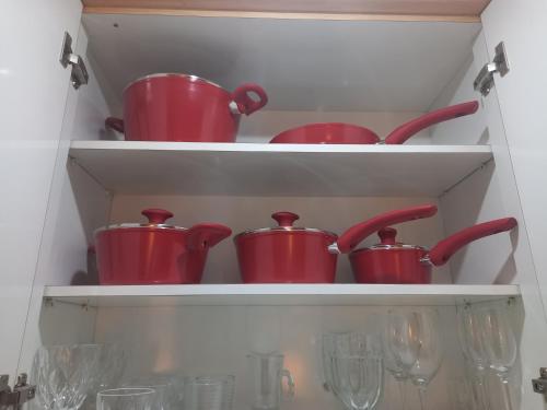 a group of red pots and pans on shelves in a kitchen at Apartamento Duplex Place Vendome! Moema, 58m2, Amplo, Conforto, Luxo! Servicos, Estacionamento, Internet, Metro! in Sao Paulo