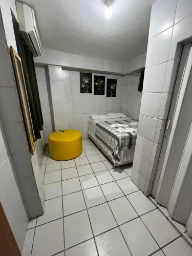a small room with a bed and a yellow stool at Pousada Shalon Olinda in Recife