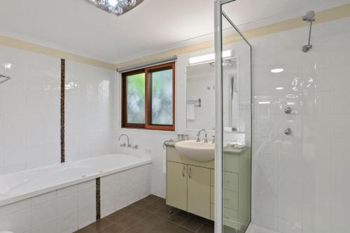 a bathroom with a tub and a sink and a shower at Kiama Harbour Cabins in Kiama