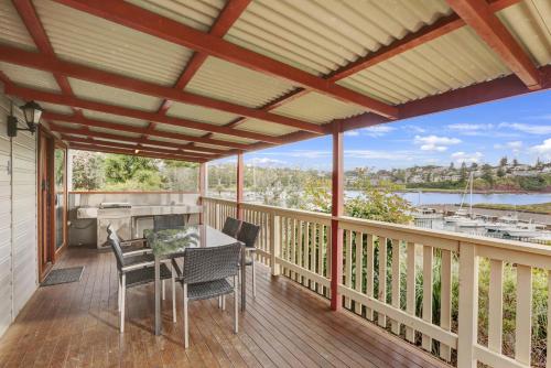 a patio with a table and chairs on a deck at Kiama Harbour Cabins in Kiama