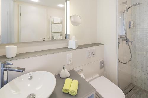 a white bathroom with a sink and a toilet at Taome Feng Shui Stadthotel Breisgau in Emmendingen
