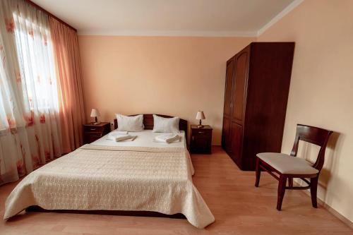 a bedroom with a large bed and a chair at Hotel Winpalace in Arbanasi